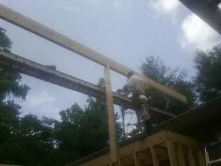 Carpenter setting a ridge beam over a new addition frame — Ice Dam Removal by Roofing Brothers in Bennett