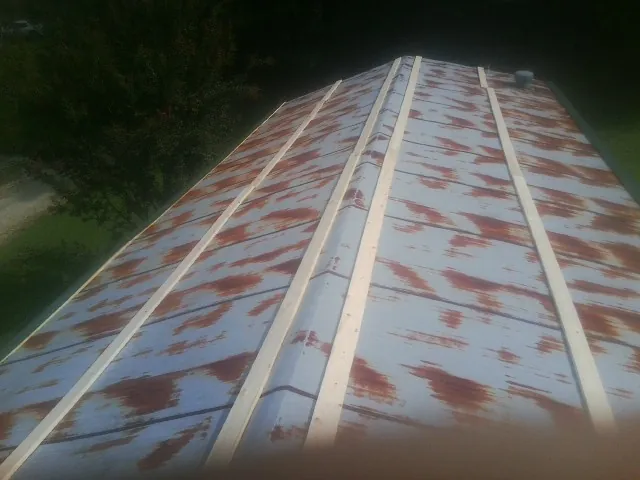 Rusted metal roof panels with new wood purlins before replacement — Storm Damage Roof Repair in Bennett by Roofing Brothers