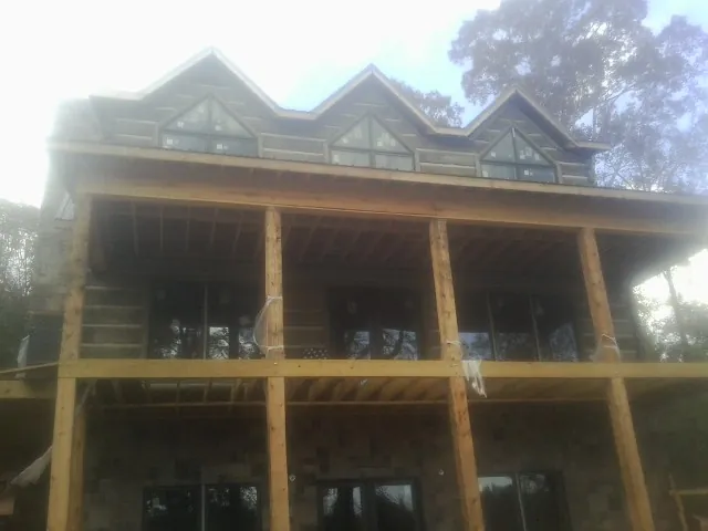 Dormers and porch framing on a large log home under construction — Roof Coating work by our crew in Bennett