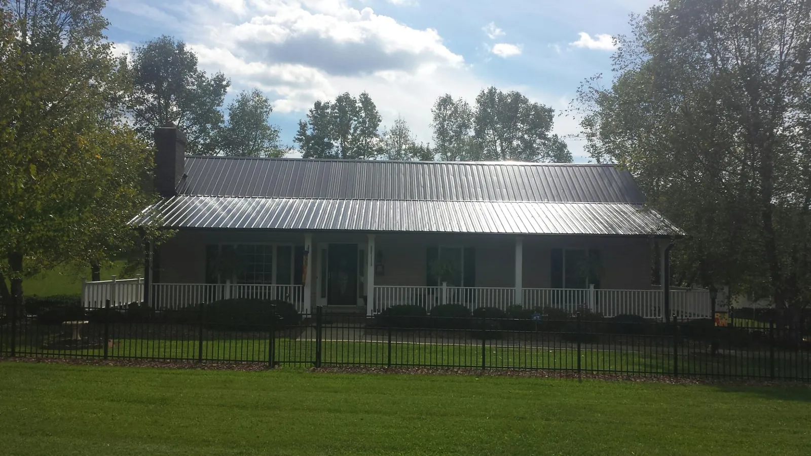 Gray metal roof on a brick ranch with a full width front porch — Gutter Guard Installation work by our crew in Bennett